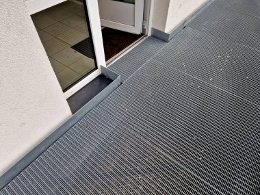 metal railings and metal grid on the floor. instead of stairs, there is a ramp for wheelchair users, a net, galvanized material. wheelchair lift. residential building, hospital entrance, senior, 