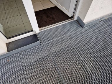 metal railings and metal grid on the floor. instead of stairs, there is a ramp for wheelchair users, a net, galvanized material. wheelchair lift. residential building, hospital entrance, senior, 