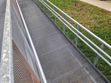 metal railings and metal grid on the floor. instead of stairs, there is a ramp for wheelchair users, a net, galvanized material. wheelchair lift. residential building, hospital entrance, senior, 