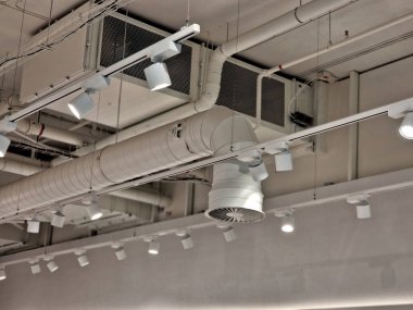 Hava kontrol ünitesi binanın tavanında ve görünürde açıkta bırakılmış. Teneke çatının altından geçen ışıklar ve borular endüstriyel bir his veriyor. tel, askıya alınmış tavan, vantilatör bobini, yükle