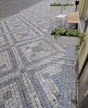 İnsanlar bir kafenin önündeki bankta oturuyorlar. Çiçek kutuları için beyaz metal yapı. Küçük bir alanda küçük bir ön bahçe. yüz oteli girişi