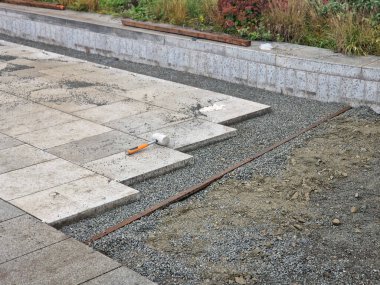 laying concrete paving in a lane between curbs. the edges of the tile cubes must be shortened and fit into the gaps. reciprocating saw. laying gravel, paving, cycle path, landscaping and earthworks clipart