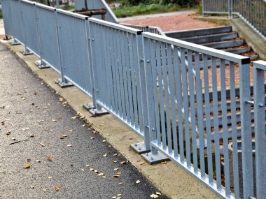  Dört beton vidayla yere sabitlenmiş çit direkleriyle köprü korkulukları. Parmaklıklar köprünün kenarından betona sabitlendi..