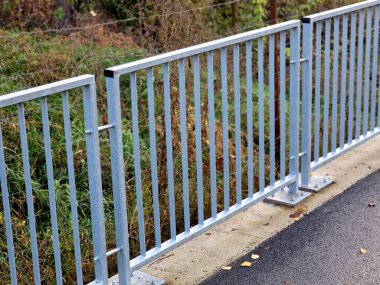  Dört beton vidayla yere sabitlenmiş çit direkleriyle köprü korkulukları. Parmaklıklar köprünün kenarından betona sabitlendi..