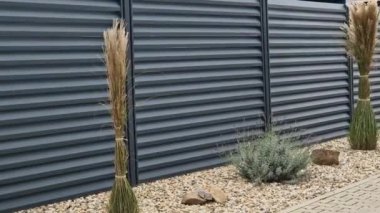 Beton bloklardan oluşan çitin metal dolguları. Metal bir alüminyum çit bahçede mahremiyet sağlayacak. Yatay kirişler iyi korunuyor. Çiçek tarhı, daimi