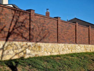 Aile evindeki tuğla duvar. Duvarın arkasında taş bloklardan yapılmış bir temel var.