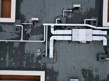 Metalden yapılmış çatı havalandırma kanalları. Isı pompası vantilatörü ve ısı değiştirici. Mutfak vantilatörü, zift yalıtımlı, düz çatı. yukarıdan dikey görünüm