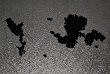 Yeraltı garajında bir yağ havuzu var. Adamın parmağında, park halindeyken araçtan sızan siyah bir yağ damlası var. Motorun altında bir kase kullan. ekolojik denetimler