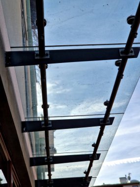 strut, suspended glass roof above the building entrance. bus station, railway station. cable wind braces. aluminum construction with windows above pergola  galvanized steel frame