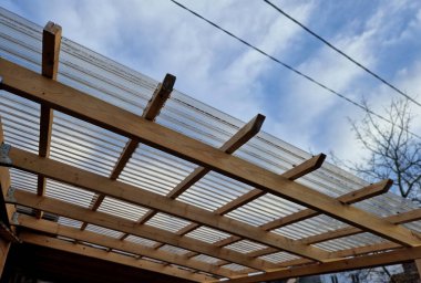 terrace with wooden pergola and plexiglass roof. vines are straining, crawling under the beams. garden or park. sitting with dry wall wine region. restaurant countryside france, truss