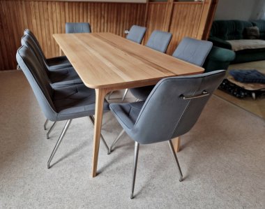 Kayın ağacından yapılmış ev yemeği masası. 8 sandalyenin etrafında döşeme ve geometrik dikişler var. Reklam amaçlarına uygun masa örtüsü olmayan boş bir masa üstü..