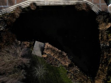 Park ziyaretçileri için iskele. İki adım ona götürür. Suyun üzerinde kalaslar var. Tekneler için rıhtımı olan bir gölet. Terasta parmaklık yok. Taş nehir kıyısı, yeşil, tekne, çimen, yüzen yapraklar, yüzer