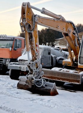 machinery such as excavators and trucks parking lot. frozen diesel and solidified oil. starting without a charged battery can be a problem. shutdown during Christmas clipart