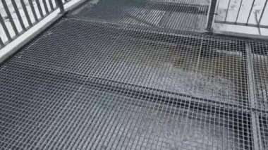 Bir adam karlı bir vadide metal bir köprüde yürüyor. galvanize metal merdiven. Kar ağların arasından düşüyor. Fabrika teknoloji kontrolü. Yapıların kaynak ve üretimi