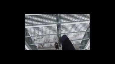 Bir adam karlı bir vadide metal bir köprüde yürüyor. galvanize metal merdiven. Kar ağların arasından düşüyor. Fabrika teknoloji kontrolü. Yapıların kaynak ve üretimi
