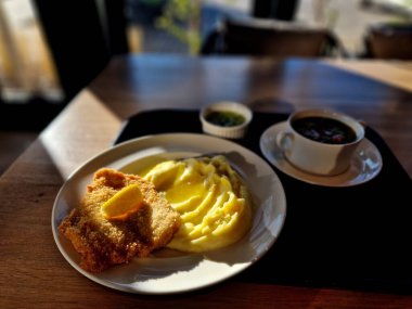 Viyana şnitzeli, böğürtlen püresi ve masanın üzerindeki okul kantininde siron. Tepsi çorbanın yanında. Ekmek kırıntıları rendelenmiş et dilimleri