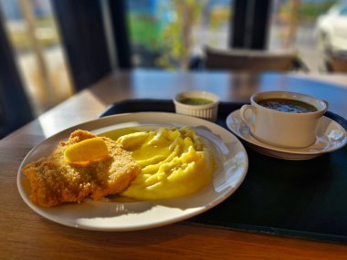 Viyana şnitzeli, böğürtlen püresi ve masanın üzerindeki okul kantininde siron. Tepsi çorbanın yanında. Ekmek kırıntıları rendelenmiş et dilimleri