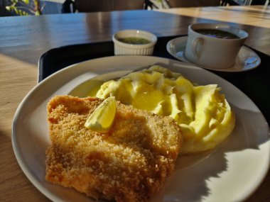 Viyana şnitzeli, böğürtlen püresi ve masanın üzerindeki okul kantininde siron. Tepsi çorbanın yanında. Ekmek kırıntıları rendelenmiş et dilimleri