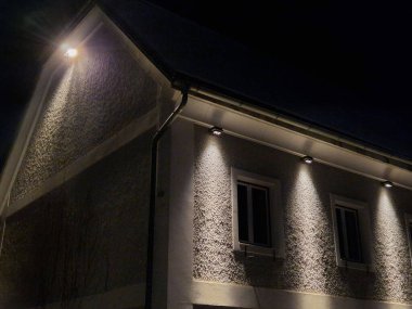 Leke duvar ışığı evin dış cephesini gece koni şeklinde aydınlatıyor. Akşam konumu ve seyrüsefer lambası Gabion duvarında iki yönde parlıyor, toz boyalı.