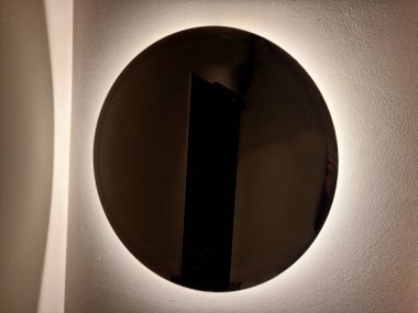 Çevresinde lamba olan dairesel ayna. Sonra arka ışıklandırması olan gri beton alçıdan basit bir ayna, karanlık bir kulüp atmosferi.