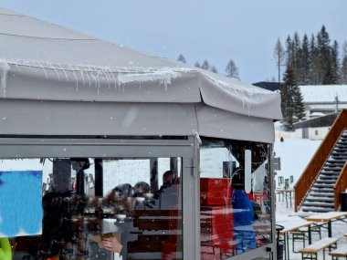 meeting up after skiing and having good drink by ski lift in Alps is great afternoon. folding sun loungers made of textile and wood with view of snowy peaks. camping benches in rows, smartphone hand clipart