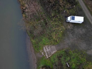 the traveler has a solar panel on the roof racks on the roof of small camper van. Very simply, he can use the sun to charge the batteries and light the inside of car, home made, meadow, white, stove clipart