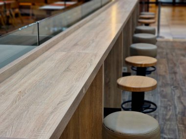 Deri döşemeli, cam bölmeli, süet döşemeli yemek masası sandalyeli daire şeklinde sandalyeler. Kafede ahşap masa ve zemin, bej.