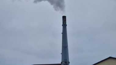 Dumanı tüten bir endüstriyel bacanın ayrıntıları. Karbondioksitli atık ve gaz yakmak çevreye zarar verir. Bulutlara karışan bir buhar bulutu