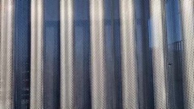 Bina kare panellerle kaplı. Metal kaplama, deniz tarağı desenli. Bükülmüş çarşaf, koyu gri, perçinlenmiş. yatay çizgiler, gölgeler, köşe, çit, alüminyum, çarşaf, otel terası