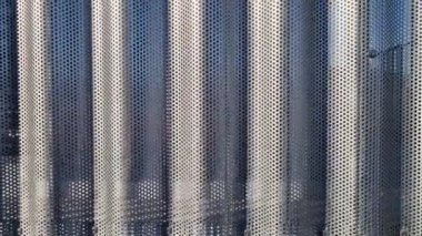 Bina kare panellerle kaplı. Metal kaplama, deniz tarağı desenli. Bükülmüş çarşaf, koyu gri, perçinlenmiş. yatay çizgiler, gölgeler, köşe, çit, alüminyum, çarşaf, otel terası
