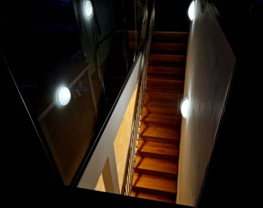 Düz, ahşap panelli merdiven manzarası. Çatı katında mutfak dolabı ışığı olan duvar, paslanmaz çelik.