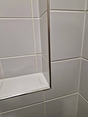 Yüze bakan fayansın kenarındaki metal şerit. Şampuanlar ve gri renk diş fırçaları için bir oyuğu olan banyo.