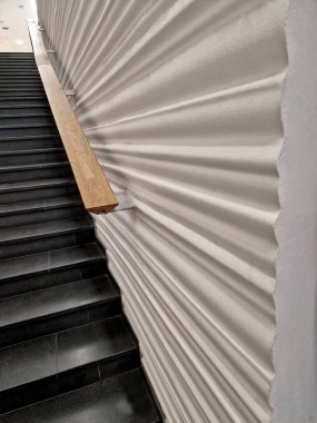 Parlak duvar panelleri ve meşe ağacından yapılmış metal parmaklıklar. Dalgalı sıva ve lüks bir görünüşü var. mermer taş koyu