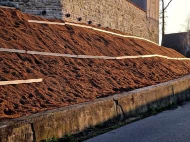 Çimento karıştırıcısının uzun düz duvarı. Duvarın arkasında duvarın içinden drenaj borularıyla çıkarılan toprak var. Kanalizasyon borusu çekiliyor. İnşaat alanı, mezarlık, gabion.