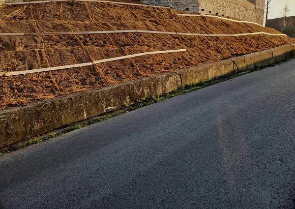 Çimento karıştırıcısının uzun düz duvarı. Duvarın arkasında duvarın içinden drenaj borularıyla çıkarılan toprak var. Kanalizasyon borusu çekiliyor. İnşaat alanı, mezarlık, gabion.