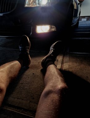 Bir arabanın önünde yerde yatan bir adam. Aracın ışıkları kaputa düşen koşucuyu kör etmiş. Yoldaki sürücülerin saldırganlığı. Sporcu şortla yerde yatıyordu.