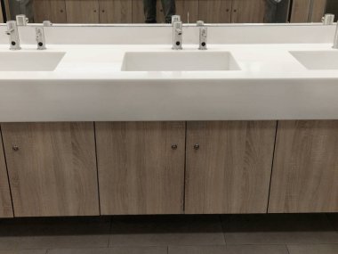 Şık çamaşır köşesi. Paslanmaz çelik sabun ve kağıt havlu makinesi. Beyaz Corian mobilya lavabosu, lavabo, musluk. Çöp kovası tezgahta, kahverengi, kilitli.
