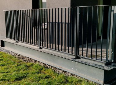 Dört beton vidayla yere sabitlenmiş dikey çit direkleriyle kule korkuluğu. Parmaklıklar köprünün kenarından betona sabitlendi..