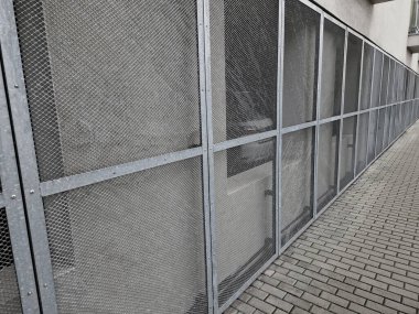 Genişletilmiş metal kafes yapısı olan bir binanın çelik kaplaması. Galvanize gri ağlar endüstriyel binayı koruyor. Gümüş arkaplan, duvar, kaldırım, lpg kontrastı