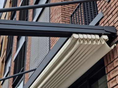 Pileli muşambayla yuvarlanan pergola. Demiryollarında genişletilebilir ve terasın üstündeki cam çatıyı gölgeleyebilir. Katlanan tekstil perdesi