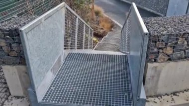 Yüksek dayanıklılığı olan taştan otoparkın yanında, galvanize çelik zemin ızgarası ve parmaklıklar altında bile dik bir merdiven inşa edilmiş. Çitin üstündeki Gabion. koridor, çiçek tarhı