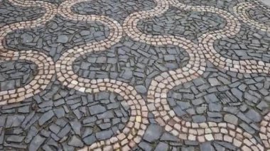 Siyah asfalttaki mozaik küplerin dalgalanma izleri. Kare ve kesik çizgiler. Meydanda dalgaların ve kalplerin tekrar eden çizgileriyle dolaş.