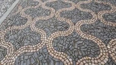 Siyah asfalttaki mozaik küplerin dalgalanma izleri. Kare ve kesik çizgiler. Meydanda dalgaların ve kalplerin tekrar eden çizgileriyle dolaş.