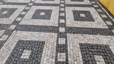 Siyah asfalttaki mozaik küplerin dalgalanma izleri. Kare ve kesik çizgiler. Meydanda dalgaların ve kalplerin tekrar eden çizgileriyle dolaş.