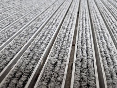 Keçeli mendil, kaset fırçası, gri alüminyum. Profiller asfalt seviyesinin altına gömülmüş. Değiştirilebilir keçeli kalemler ayakkabıları temizler ve suyu emer. Kayma riski azaldı.