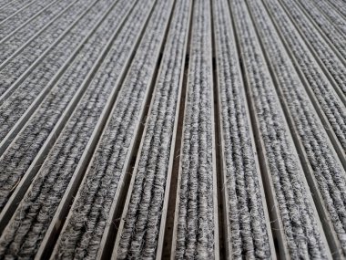 Keçeli mendil, kaset fırçası, gri alüminyum. Profiller asfalt seviyesinin altına gömülmüş. Değiştirilebilir keçeli kalemler ayakkabıları temizler ve suyu emer. Kayma riski azaldı.