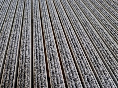 Keçeli mendil, kaset fırçası, gri alüminyum. Profiller asfalt seviyesinin altına gömülmüş. Değiştirilebilir keçeli kalemler ayakkabıları temizler ve suyu emer. Kayma riski azaldı.