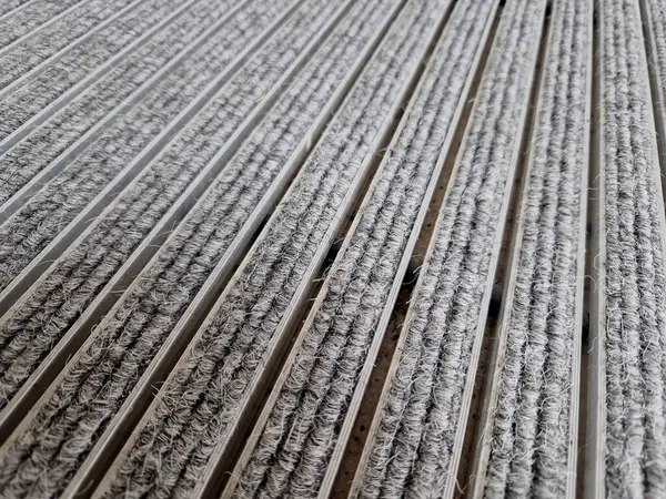 Keçeli mendil, kaset fırçası, gri alüminyum. Profiller asfalt seviyesinin altına gömülmüş. Değiştirilebilir keçeli kalemler ayakkabıları temizler ve suyu emer. Kayma riski azaldı.