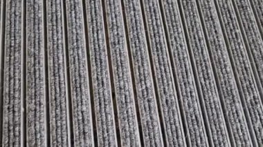 Keçeli mendil, kaset fırçası, gri alüminyum. Profiller asfalt seviyesinin altına gömülmüş. Değiştirilebilir keçeli kalemler ayakkabıları temizler ve suyu emer. Kayma riski azaldı.