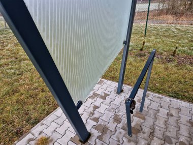 modern design of bus stop, tram in the city. a seat, a bench with a glass back covered with fresh morning frost. hoarfrost on glass board.